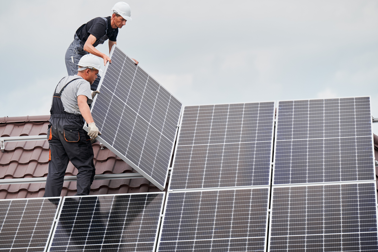 man worker mounting solar panels on roof of house.